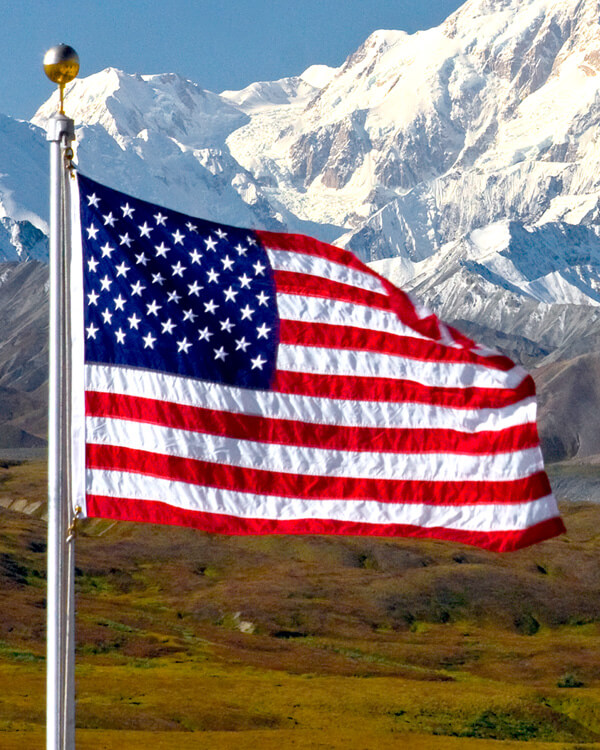 American flag on a pole in front of snow covered mountains